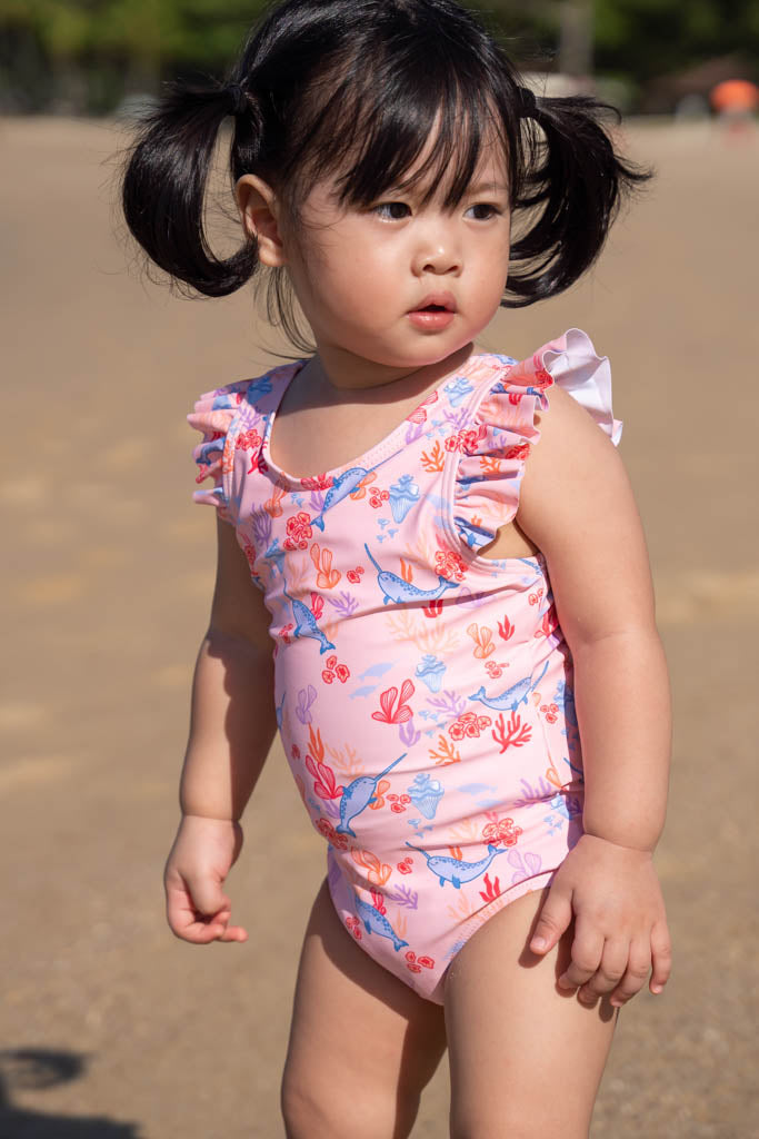Toddler in pink swimsuit at the beach