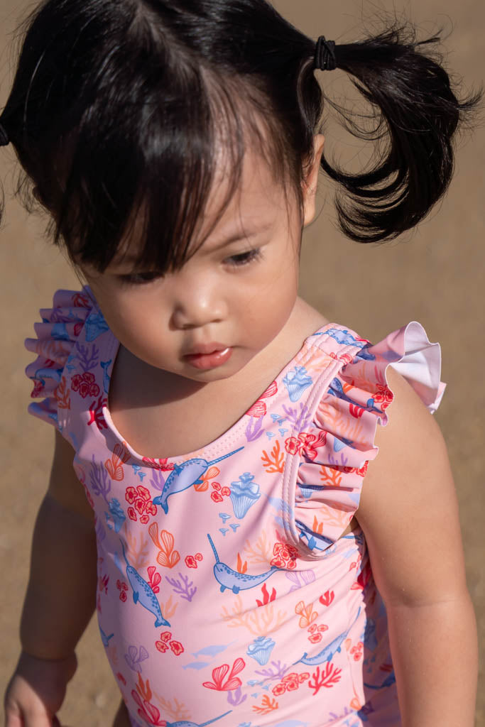 Toddler girl in pink swimsuit with pigtails