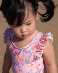 Toddler girl in pink swimsuit with pigtails