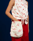 Woman wearing patterned top and red pants with matching bag