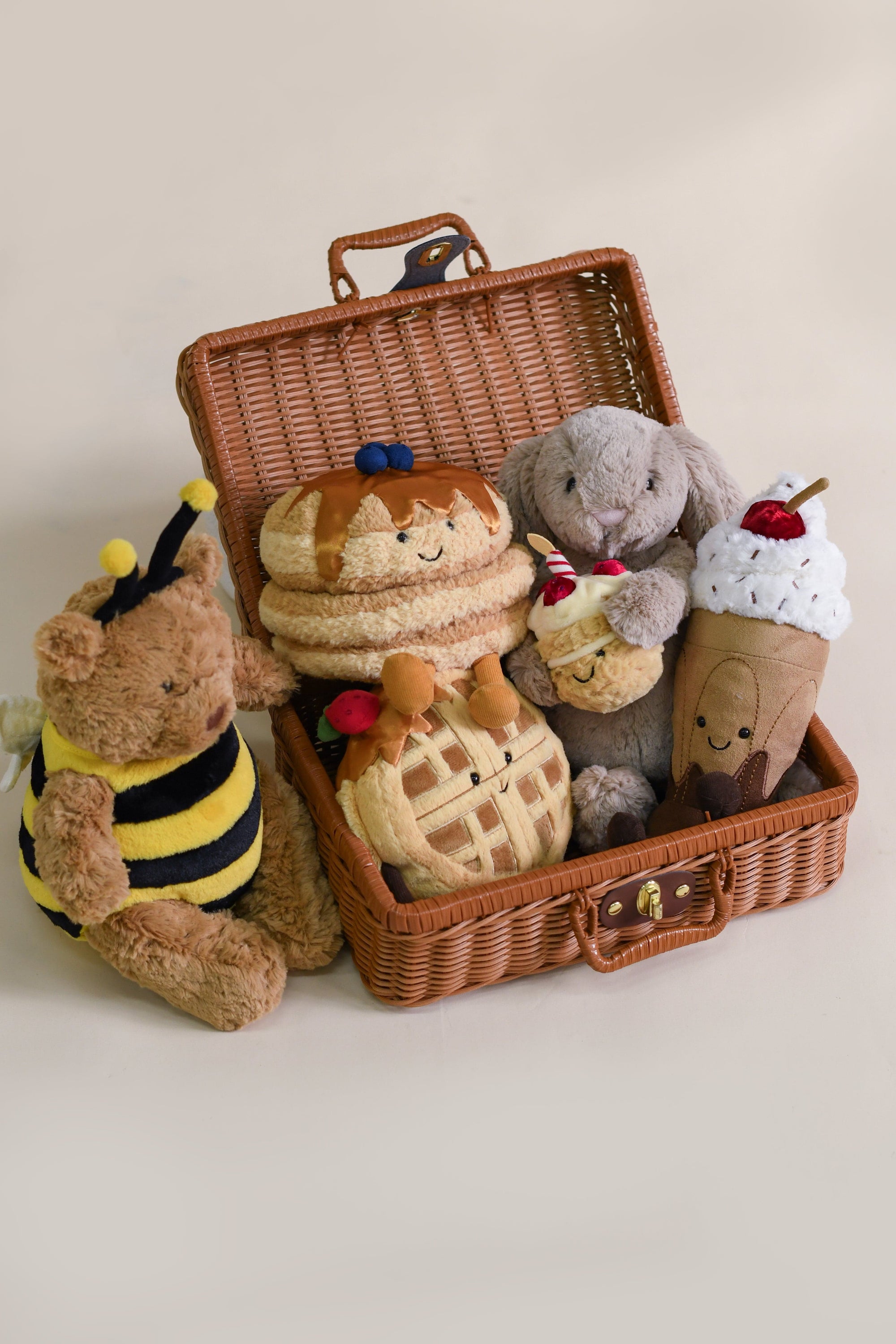 Stuffed toys in picnic basket, including bear, bunny, pancakes, and waffle.