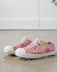 Pink donut print shoes with white soles being rinsed under running water.
