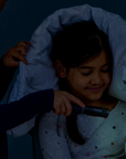 Girl playing with glowing toy under a blanket