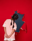 Girl in Stitch tee shirt looking through hole in red wall.