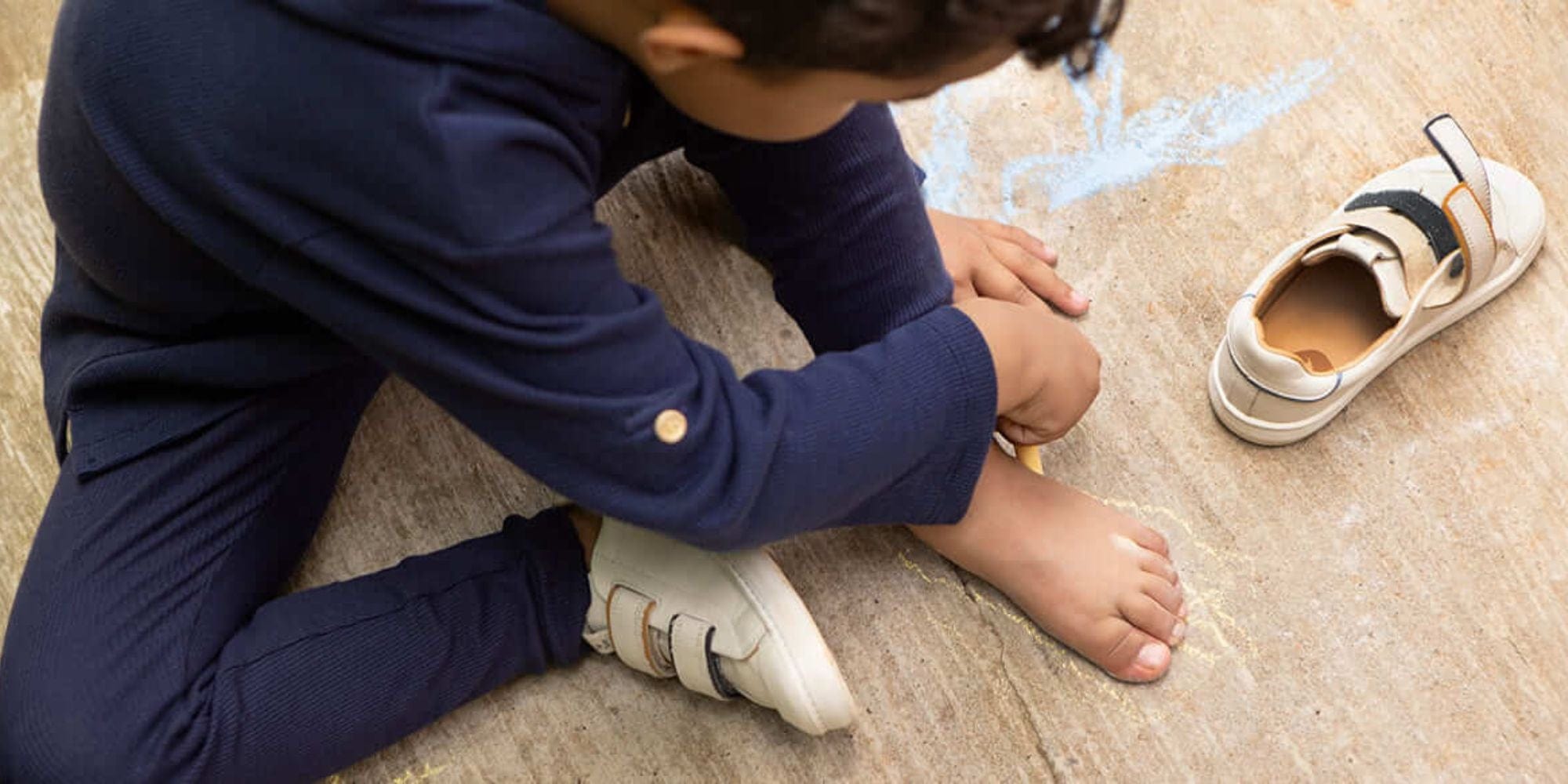Kid drawing on foot with shoe nearby