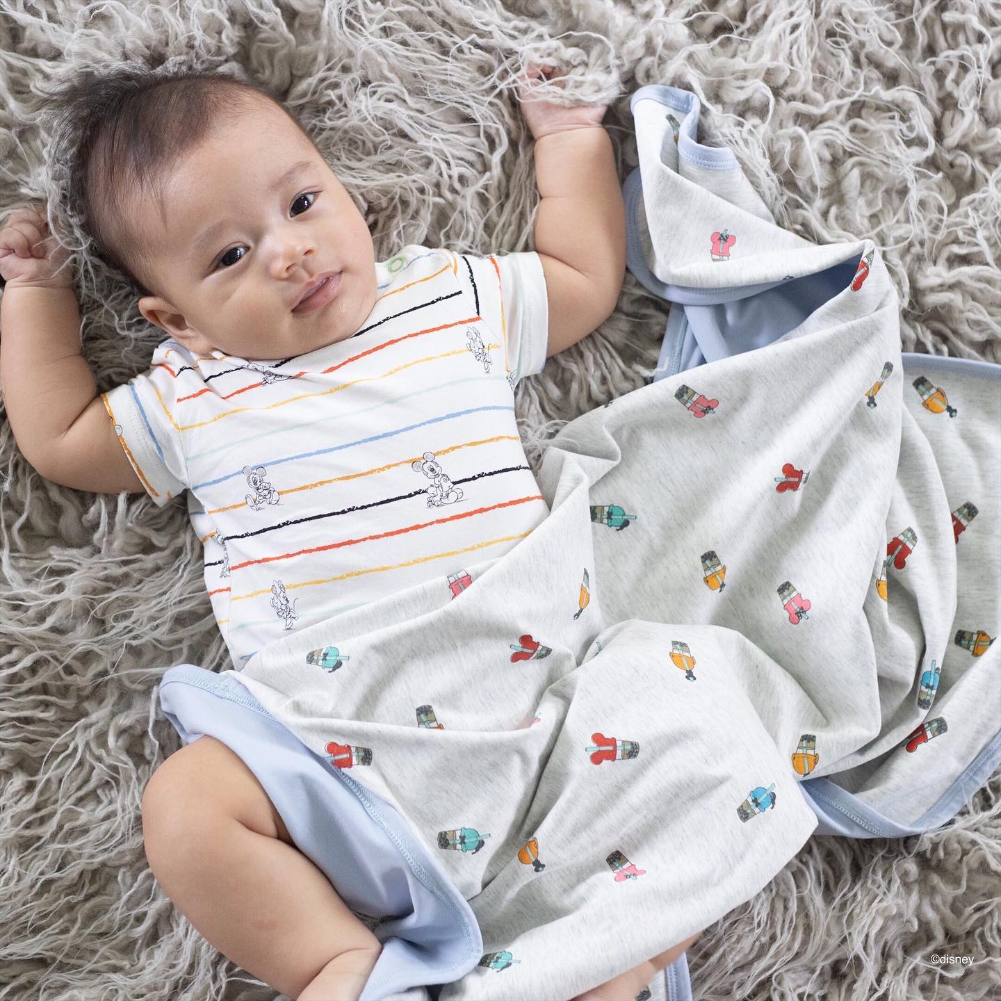 Baby with blanket on soft rug