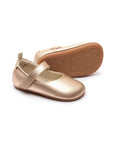 Pair of metallic salmon pink leather Mary Jane baby shoes featuring a soft-sole design and adjustable strap.