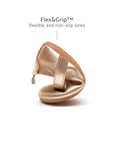 A metallic salmon baby shoe being flexed to showcase the lightweight, non-slip rubber sole for natural movement.