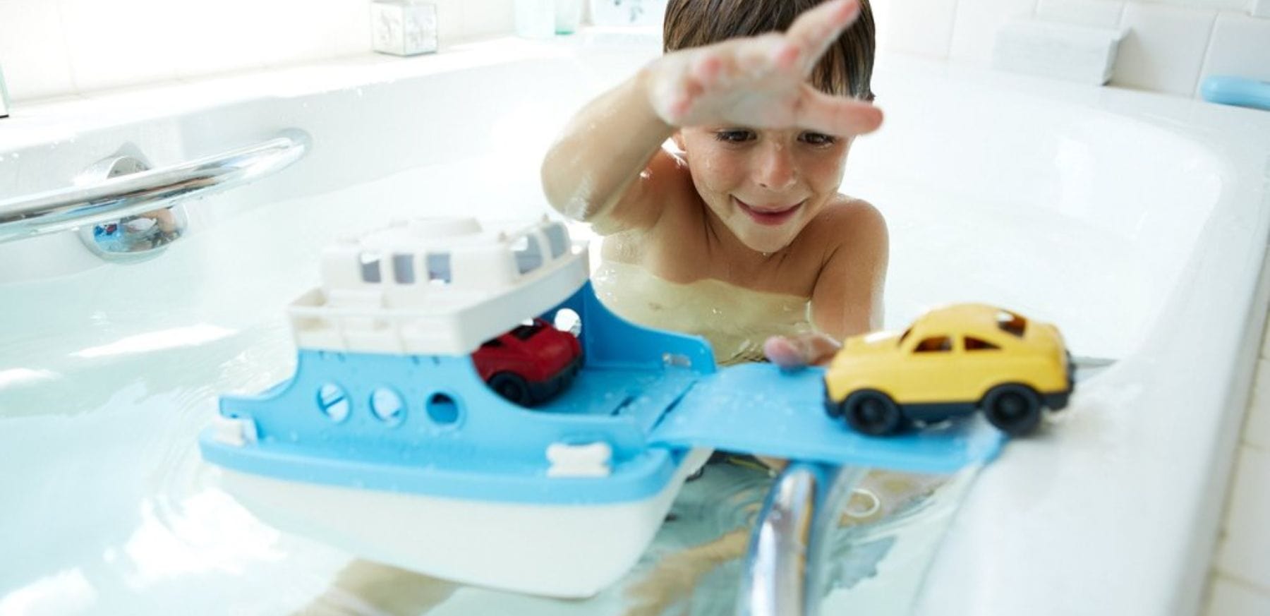 Boy playing with toy boat & car.