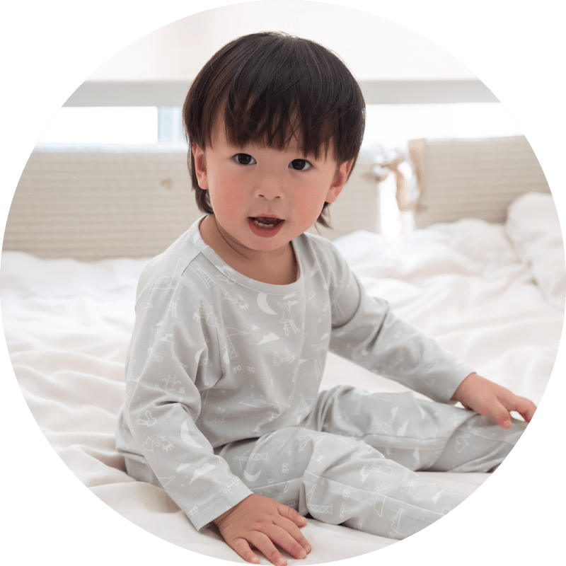 Child in pjs smiling on bed