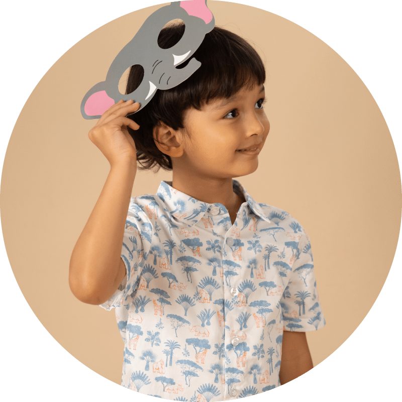 Boy in patterned shirt holding elephant mask