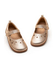 Angled view of kids metallic salmon Mary Janes showing the secure strap and decorative heart toe detail.