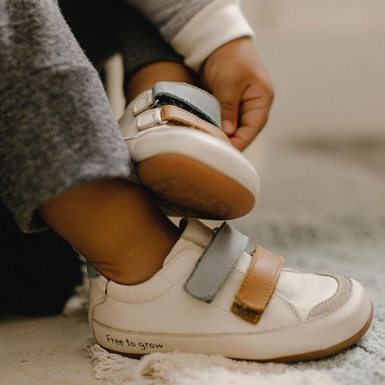 Child's feet wearing white sneakers.