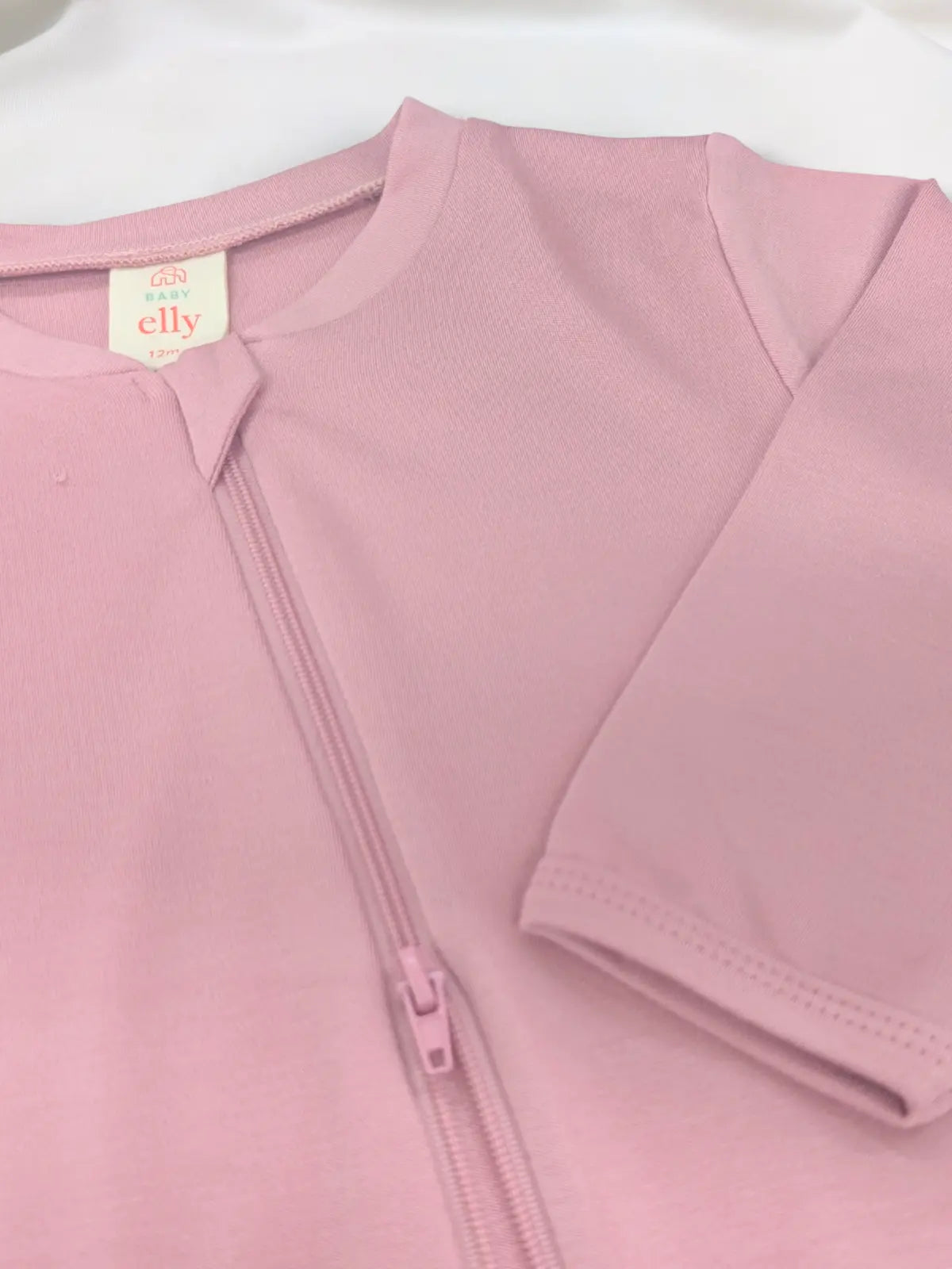A closeup of pink baby sleepsuit on a white background
