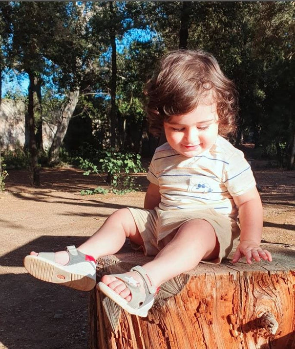 Biomecanics sandals on toddler sitting on log