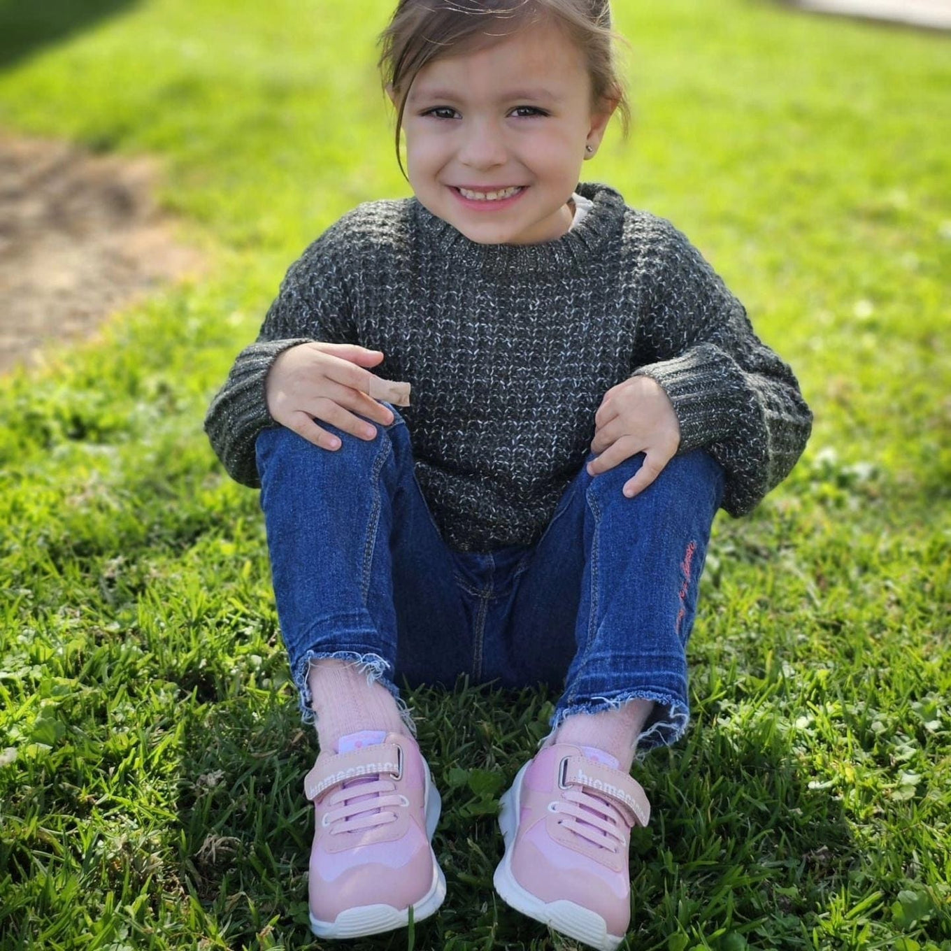 Girl in pink shoes smiling on grass