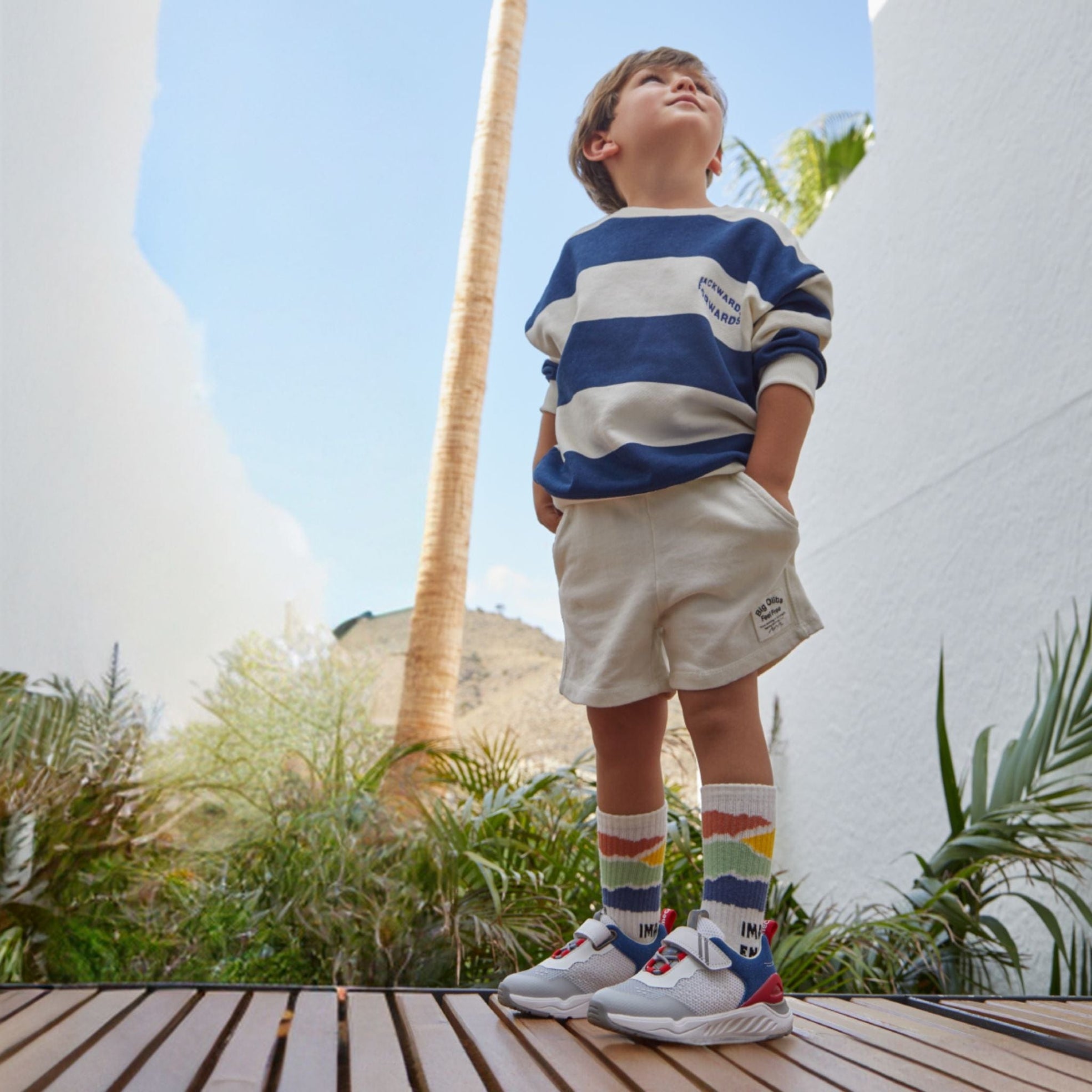 Boy in blue stripe shirt & shorts looking up