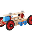 A wooden toy car chassis with red wheels, blue and orange drive wheels, and a light natural wood body, shown on a plain white background.