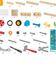 Brio 136-piece wooden building blocks set shown with all included pieces and tools laid out on a white background, including wooden beams, peg boards, wheels, screws, wrenches, a hammer, and a package insert.