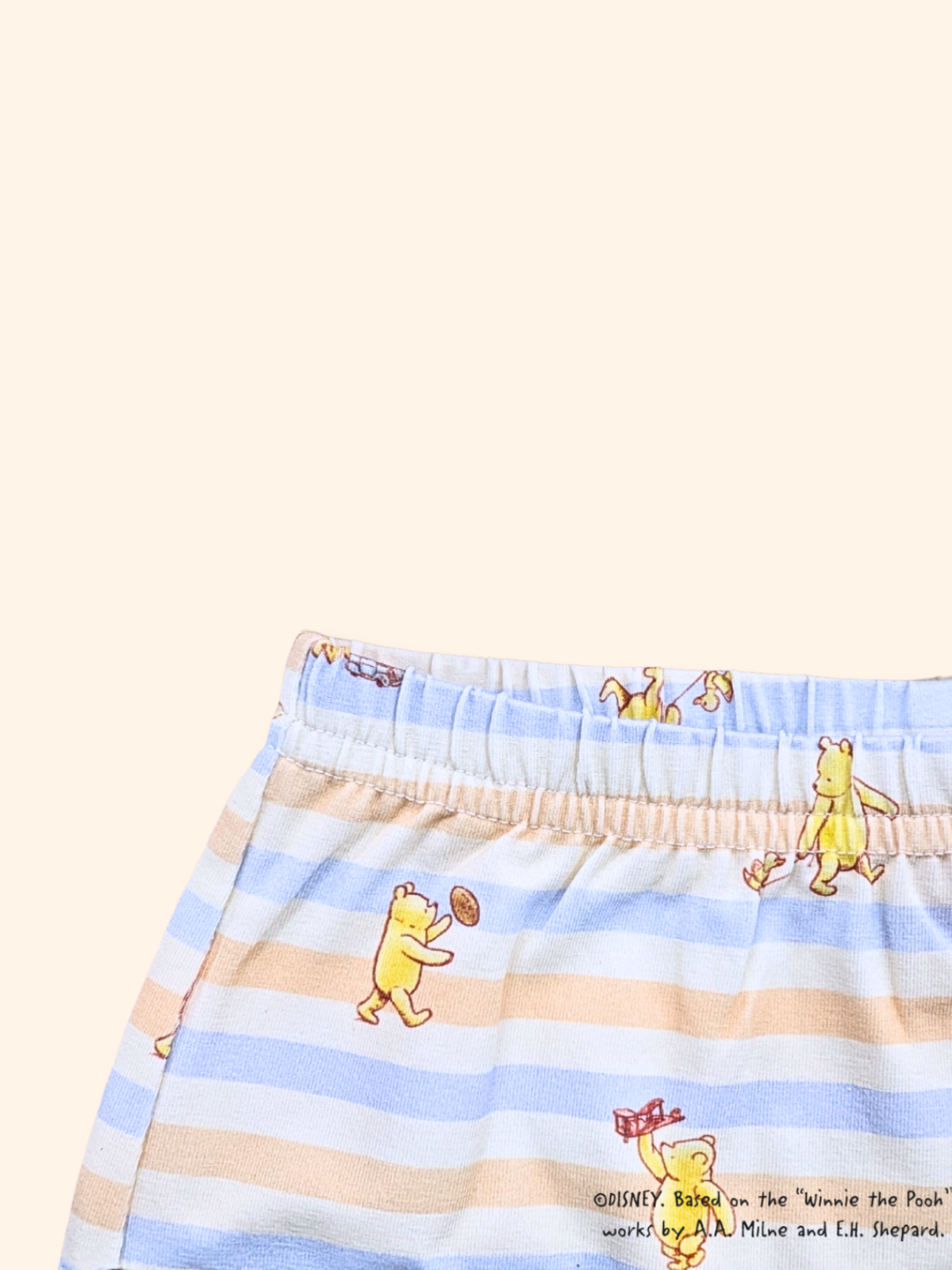 Close-up of elastic waistband on baby leggings with blue stripes and Pooh design