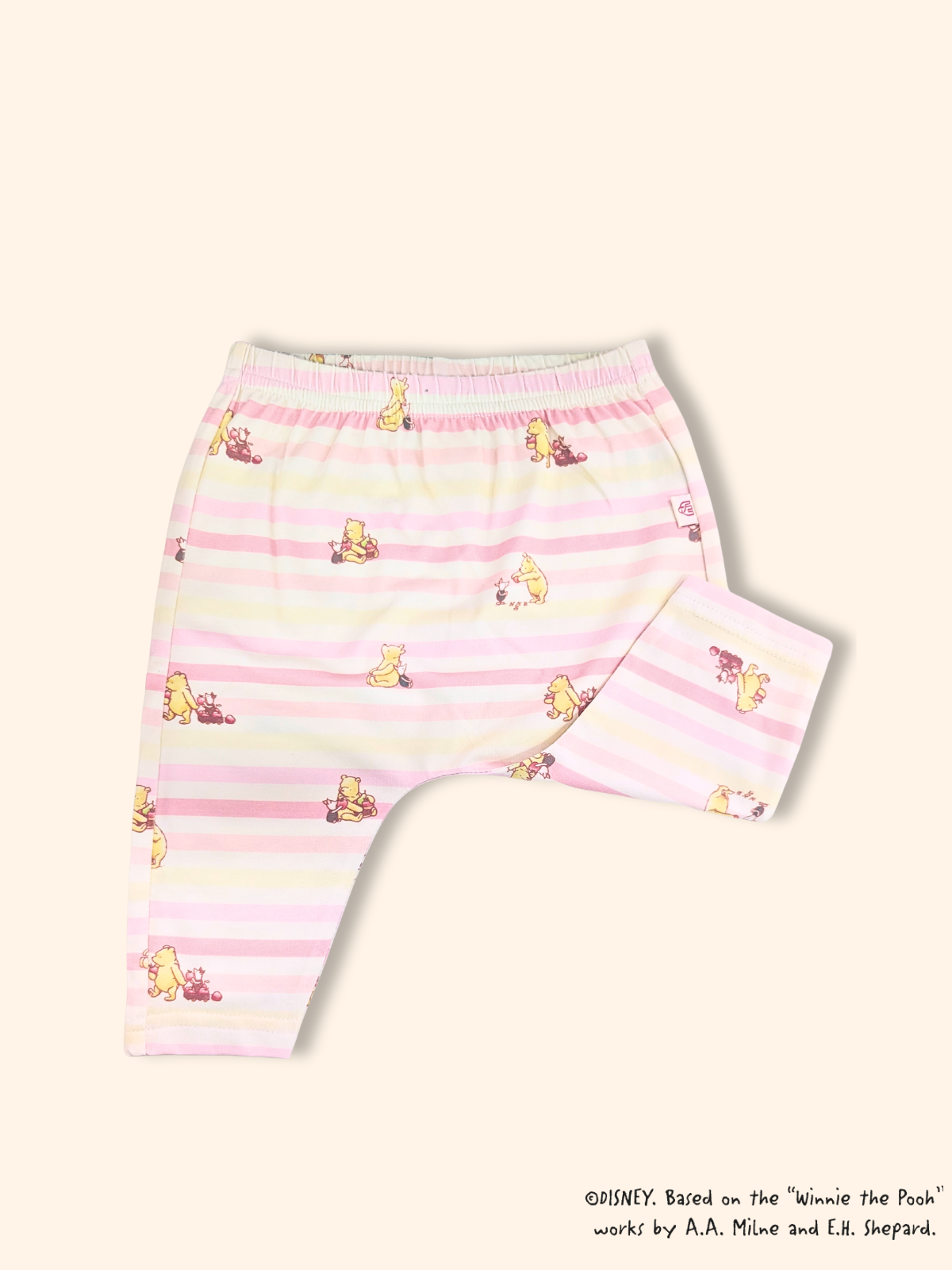 Close-up of baby leggings with pink striped Pooh print, soft stretch fabric and elastic waistband