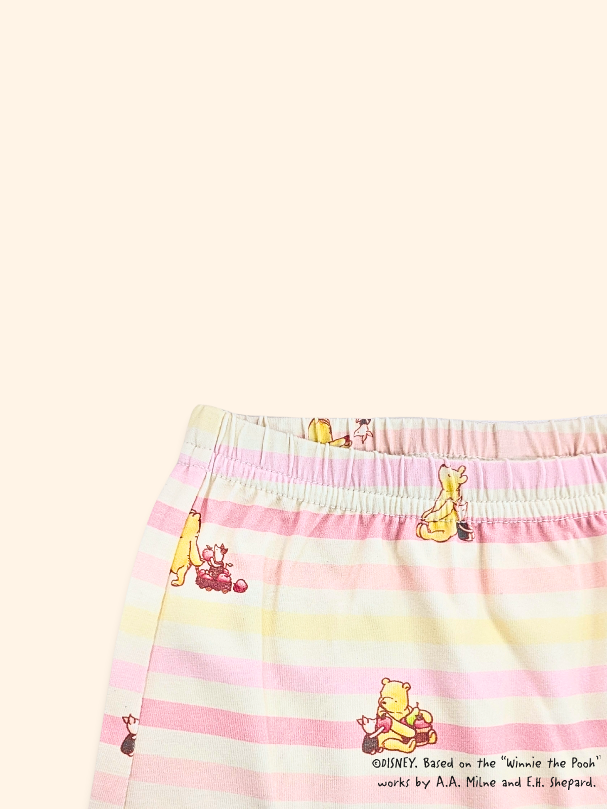 Close-up of elastic waistband on baby leggings with pink stripes and Pooh design