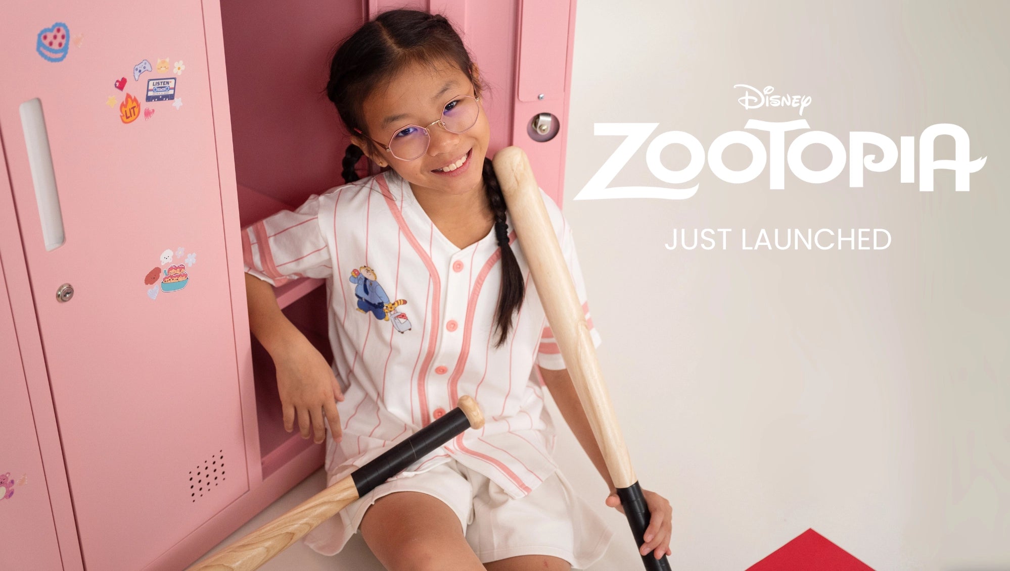 Child sitting inside a pink locker with a 'Zootopia' theme, holding a baseball bat.