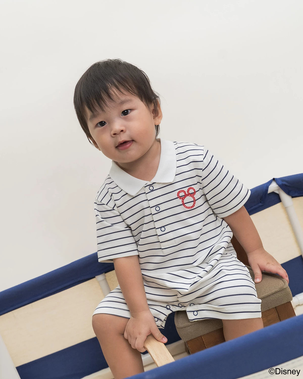 Child wearing Short-Sleeve Polo Romper - Stripes Sailor Mickey
 sitting on a chair.