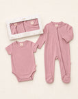 Pink baby bodysuit and onesie set on a light background