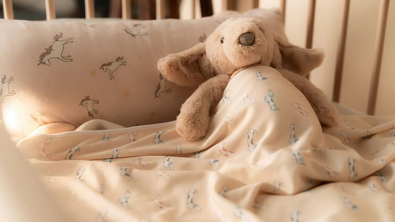 Cute teddy bear wrapped in a patterned blanket in a crib