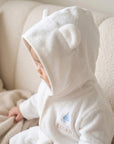 Side view of baby in white hooded bear bathrobe showing embroidery and soft texture