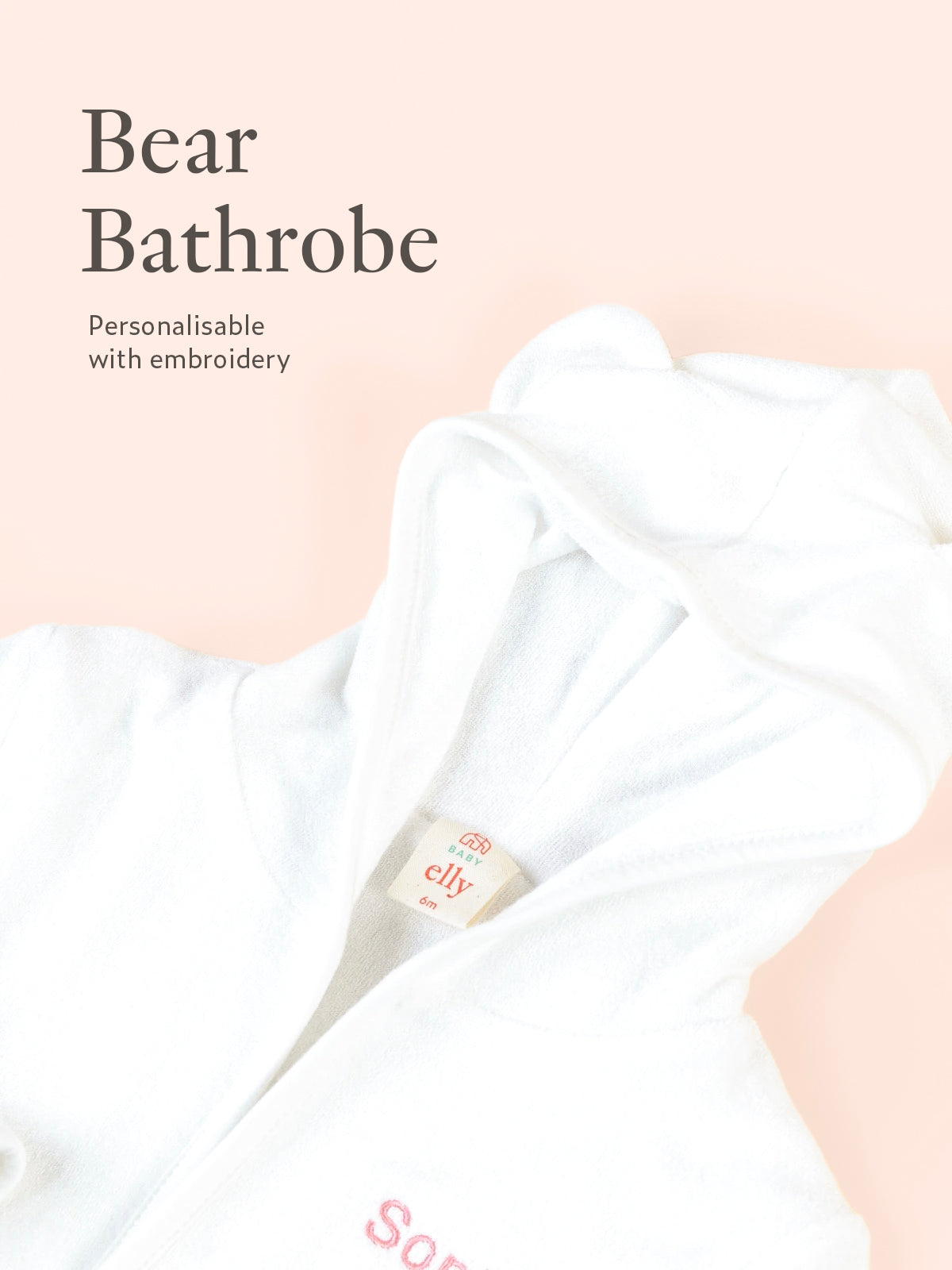 Close-up of personalised white Bear bathrobe embroidery detail on soft neutral background