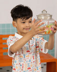 Boy holding a candy jar wearing the Childhood Games Polo Tee by Elly.