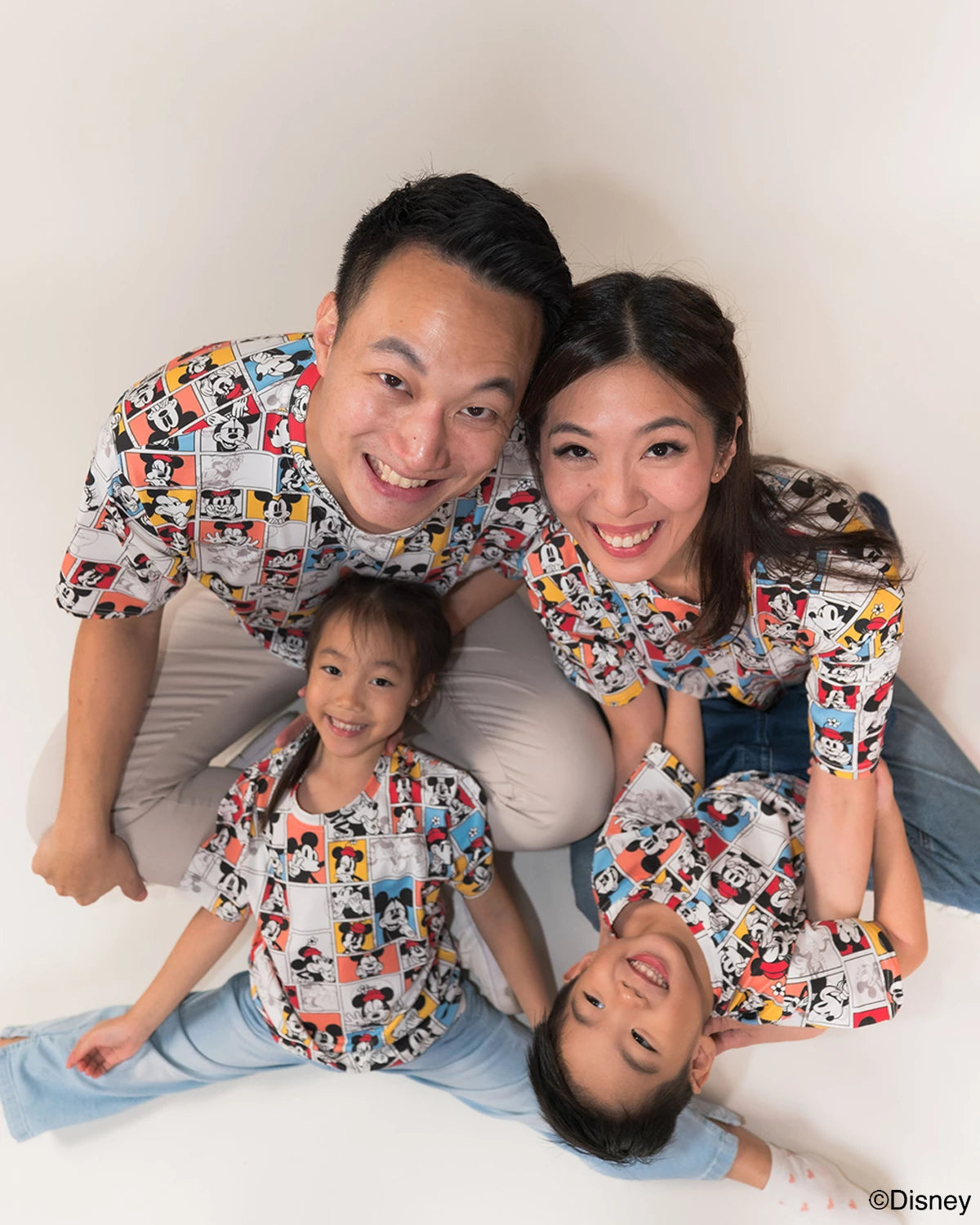 Family of four wearing matching pop comic mickey tees on a white background.