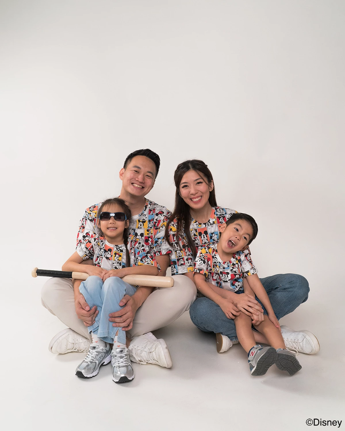Family of four wearing matching pop comic mickey tees on a white background.