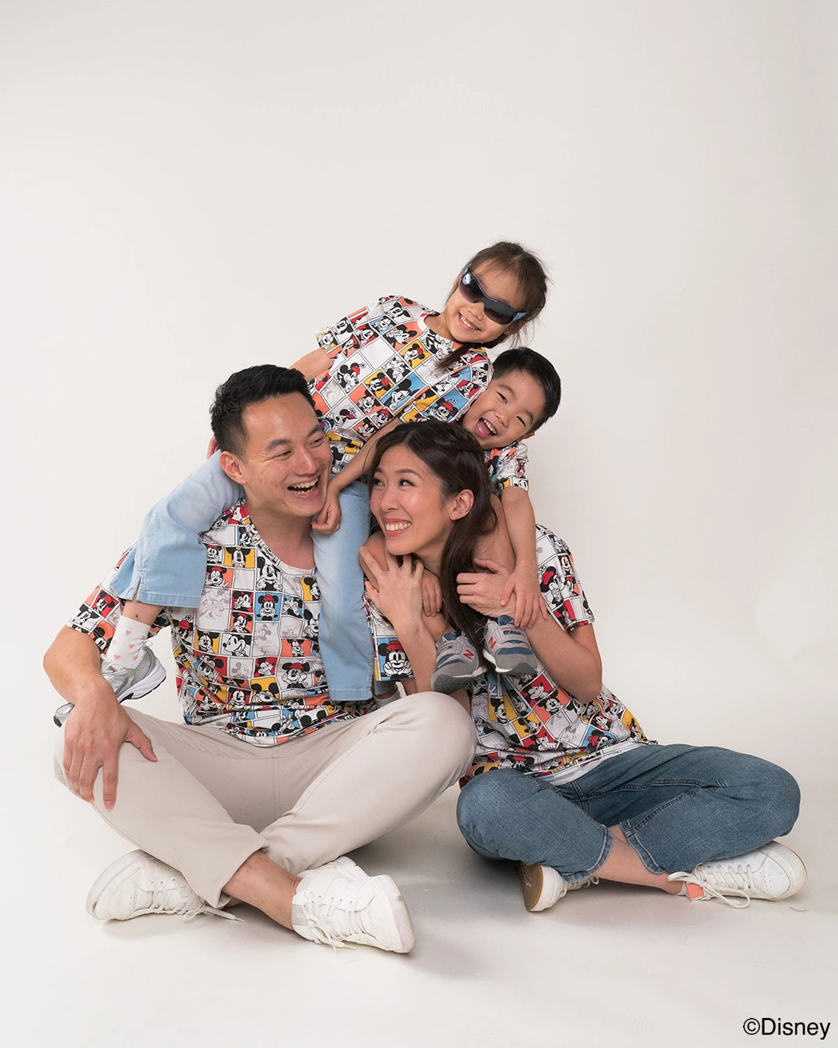 Family of four sitting on the floor against a white background, wearing matching tees
