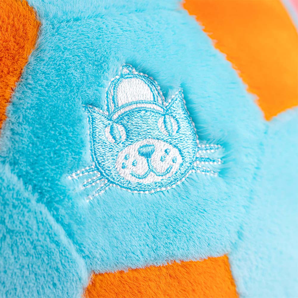 Close-up of a plush toy with a cat face design on a blue and orange background