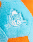 Close-up of a plush toy with a cat face design on a blue and orange background