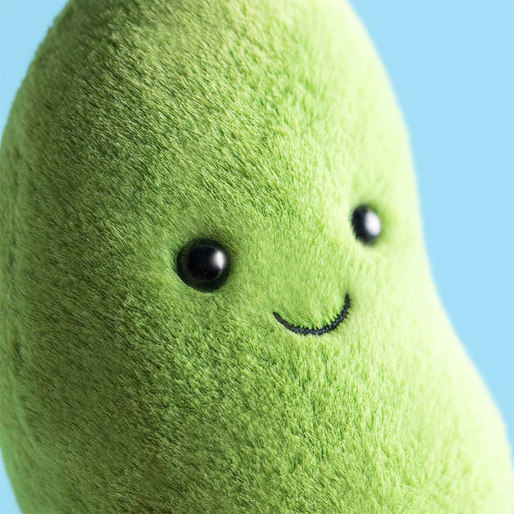 Plush greenbean toy with a smiling face against a blue background