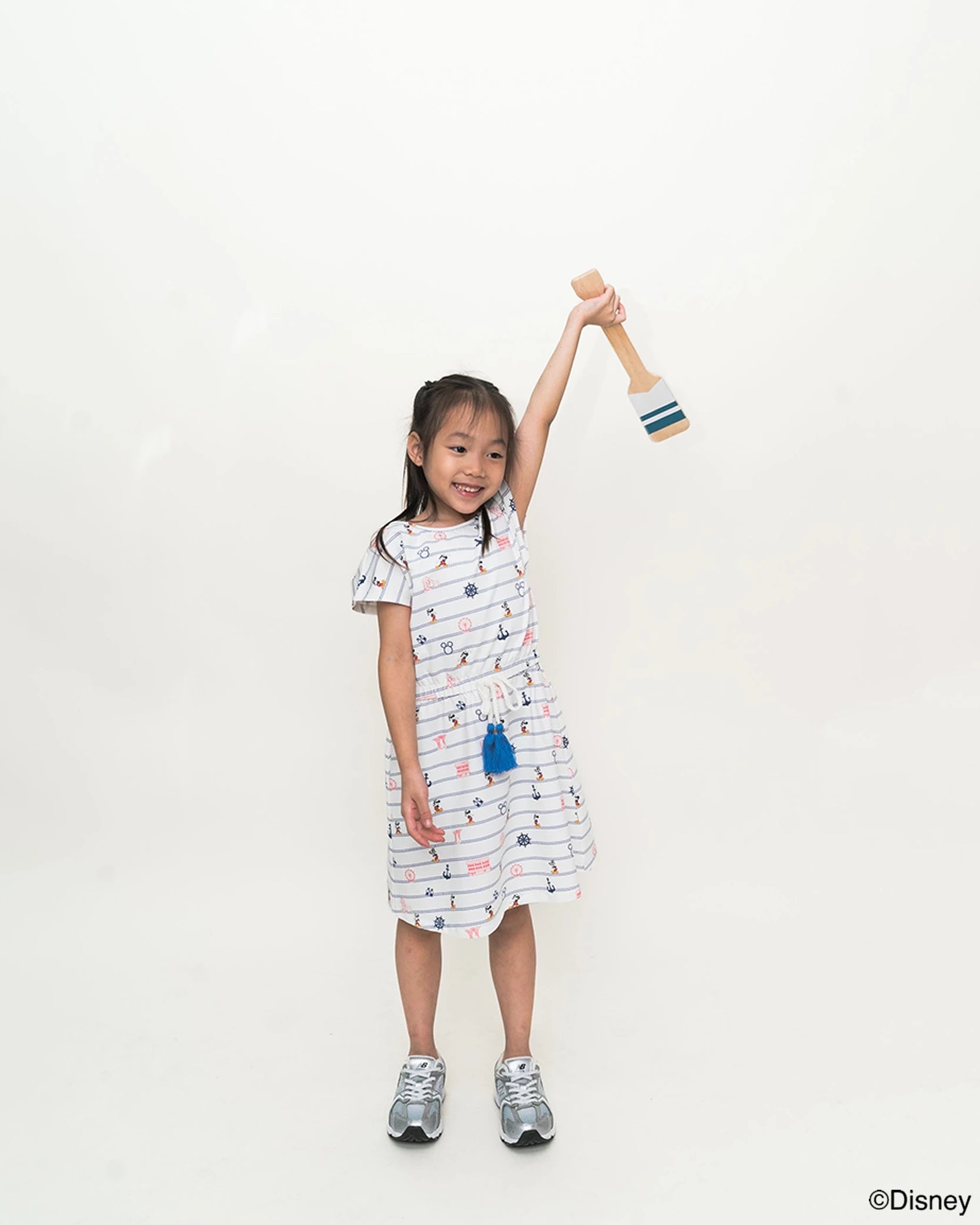 Child wearing hayley dress in nautical mickey holding a toy against a plain background