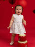Baby girl wearing Elly Kira Onesie in Zodiac Mahjong print standing by a red drum.