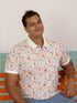 Men's Childhood Games Polo Tee by Elly - Front view of man in signature print sitting on a bench.