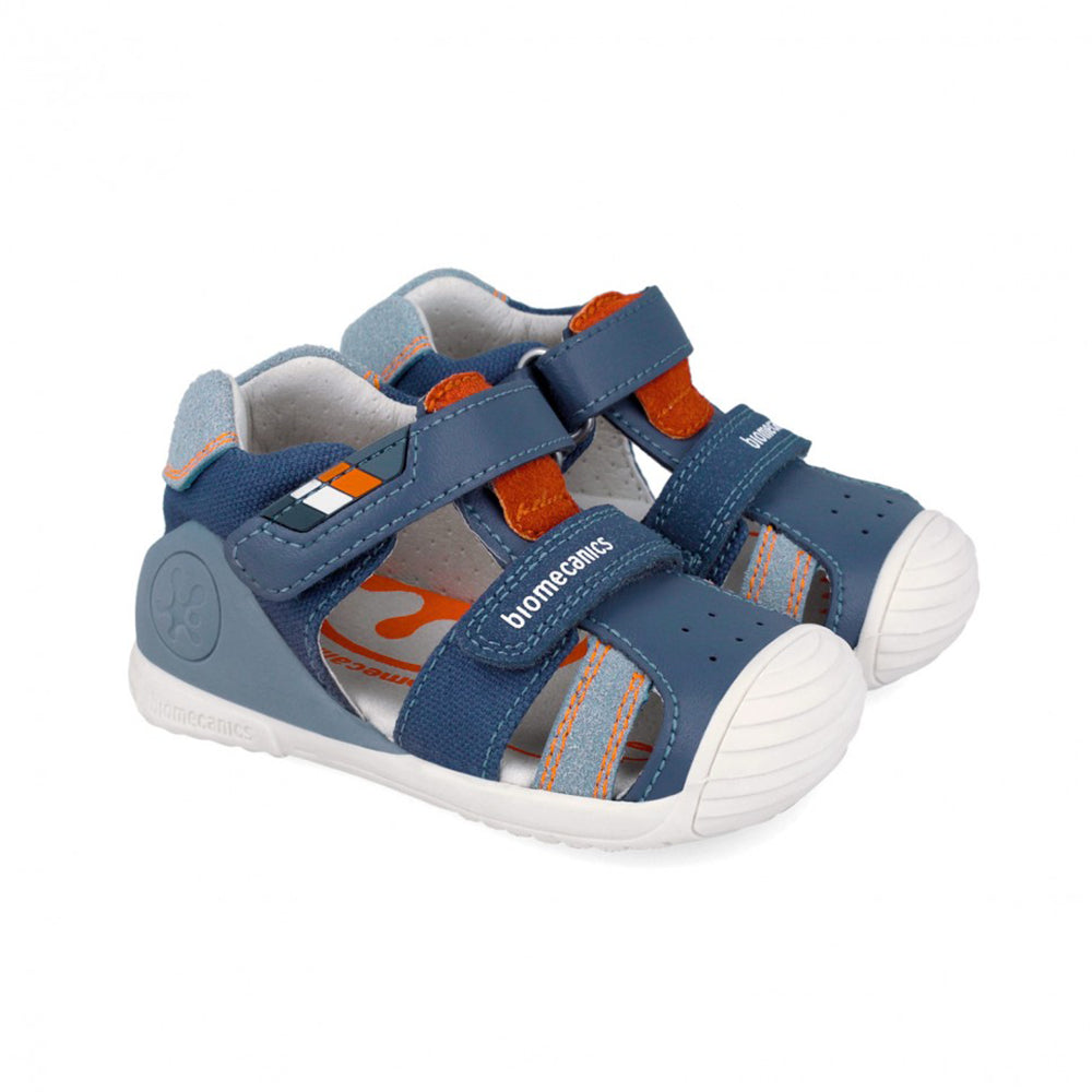 Blue children's sandal with orange accent and white sole on a white background