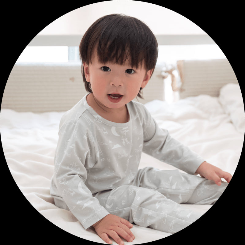 Child in pjs smiling on bed