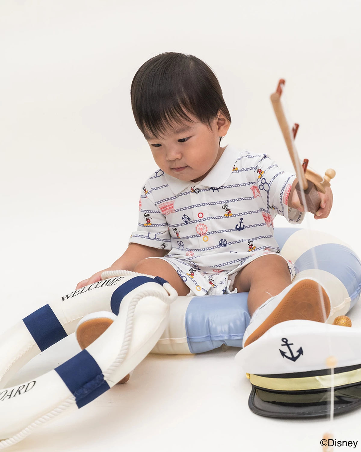 Child playing with a toy lifeboat on a white background