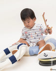Child playing with a toy lifeboat on a white background