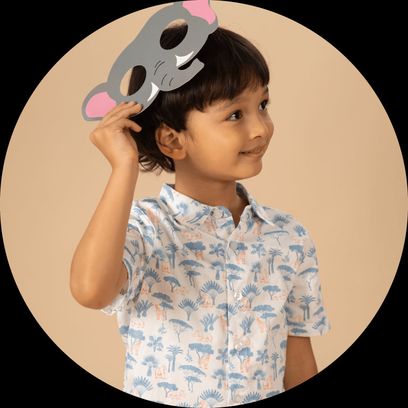 Boy in patterned shirt holding elephant mask