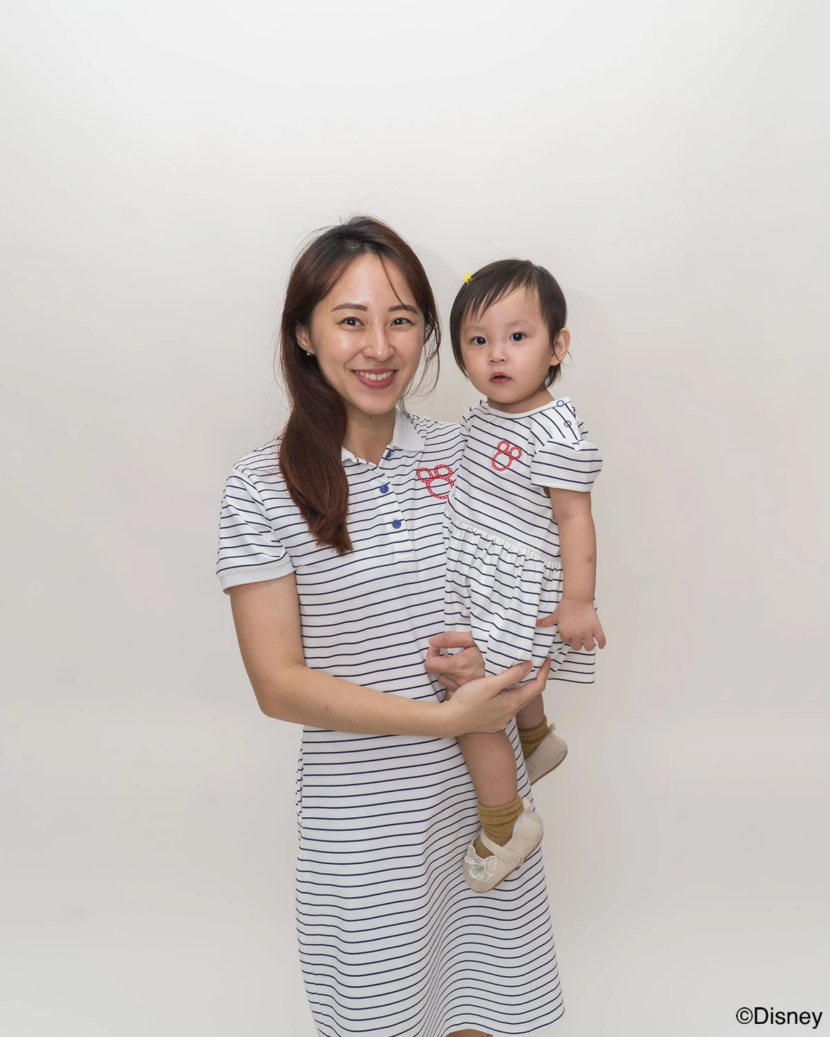 Woman holding a child both wearing matching stripes sailor mickey design 