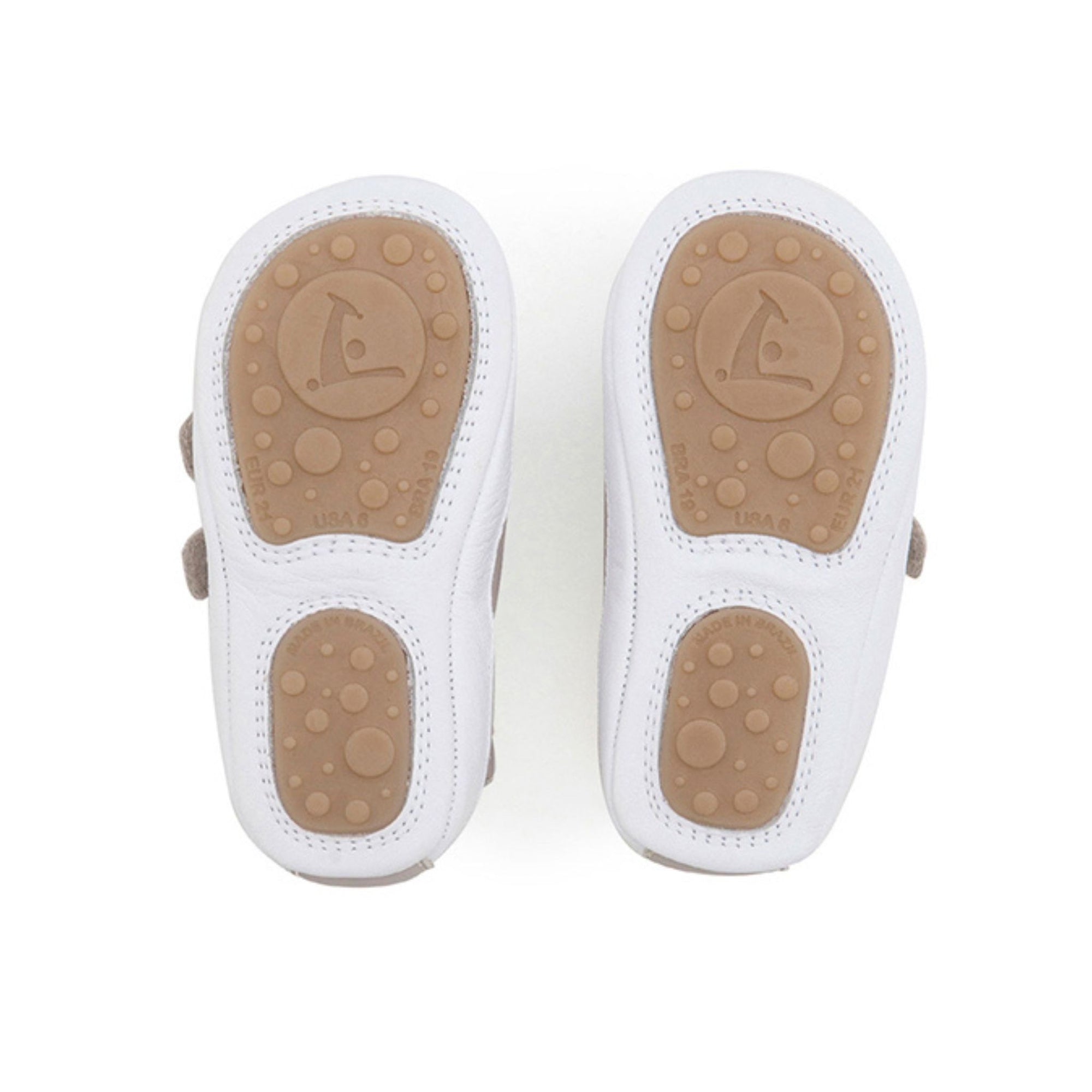 Bottom view of Bossy baby sneakers showing the split rubber traction pods on the white flexible sole.