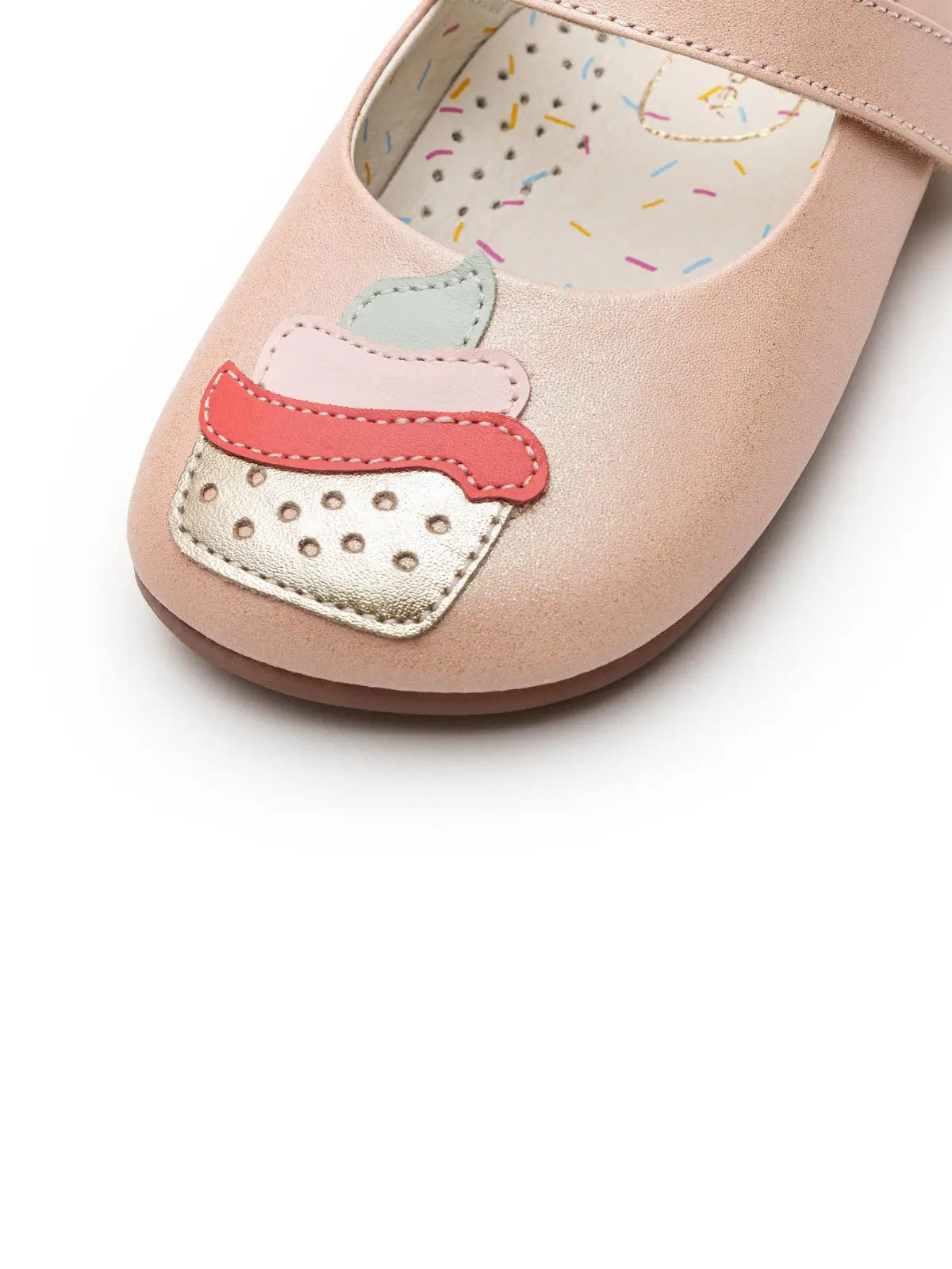 Close-up of the cupcake applique on the toe of the shoe, showing layered leather details in pink, mint green, and gold.